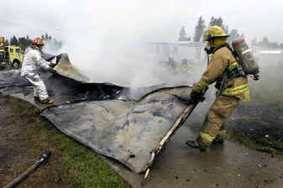 Firefighters mop up after a fire destroyed a mobile home at the Airway Express Trailer Park on the 3800 block of South Geiger Boulevard on Thursday. The home was engulfed when firefighters from Spokane County Fire District 10 arrived. The blaze is under investigation.
(Colin Mulvany / The Spokesman-Review)