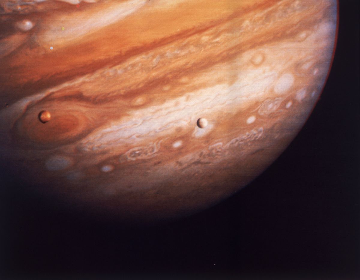 Jupiter, the largest planet in our solar system, with two of its satellites, Io on the left (above Jupiter’s Great Red Spot) and Europa on the right, in March 1979. The image was taken by the Voyager 1 spacecraft.  (Space Frontiers)