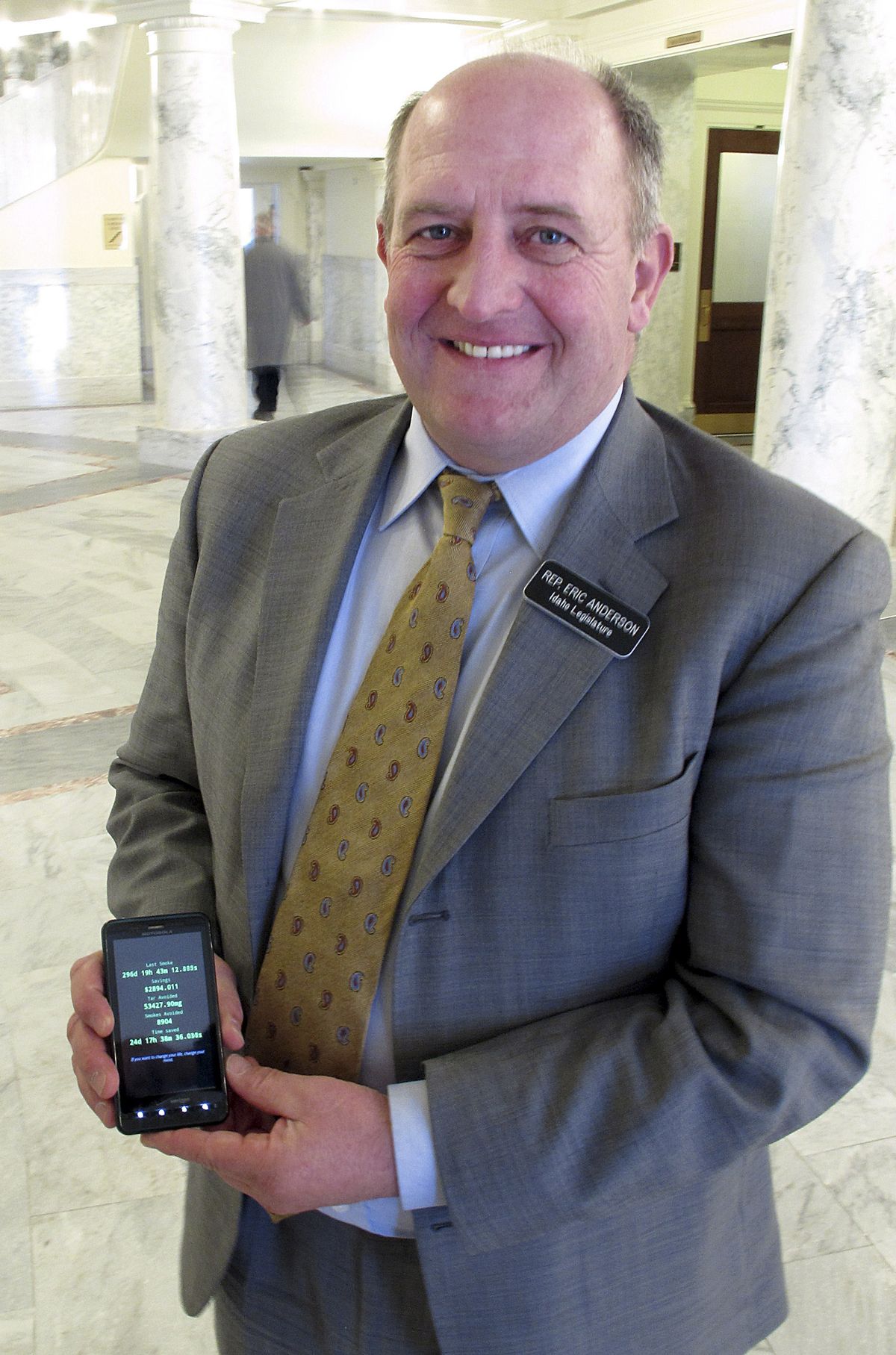 Rep. Eric Anderson poses Monday with a smartphone showing how many days it’s been since he quit smoking last April. Anderson quitting left Rep. Bob Nonini as the lone Statehouse smoker. (Associated Press)