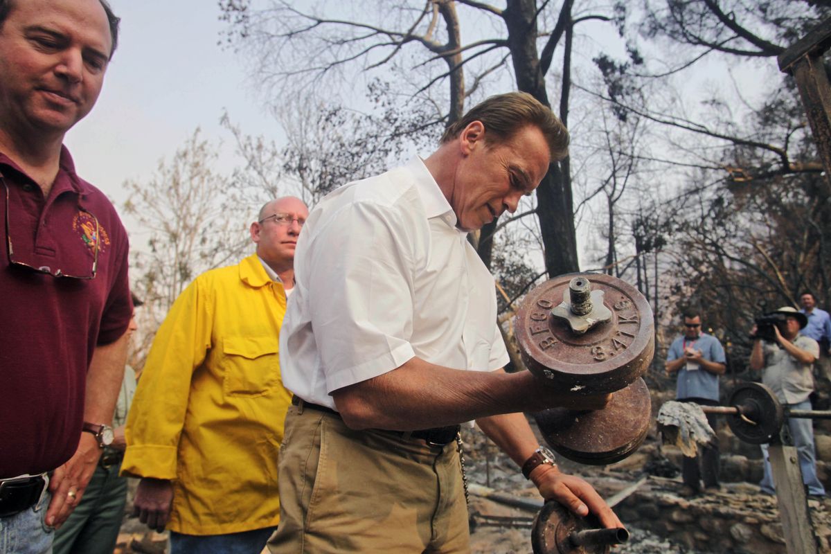 California Gov. Arnold Schwarzenegger picks up a dumbbell in a burned-out home in Tujunga, Calif. (The Spokesman-Review)