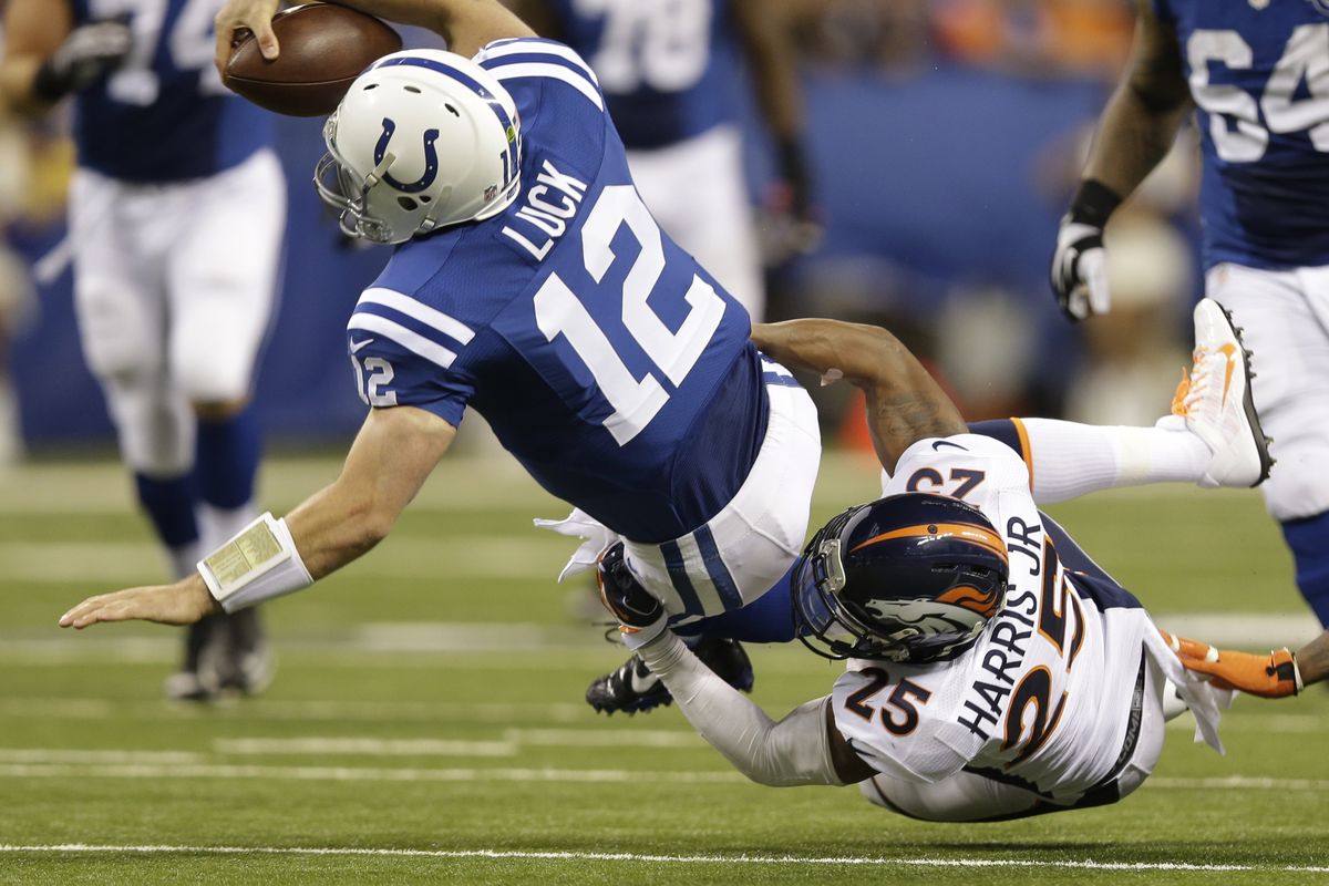 Andrew Luck scrambles for 11 yards before being tackled by Broncos’ Chris Harris. Luck ran for 29 yards, including a touchdown. He threw for 3 more. (Associated Press)