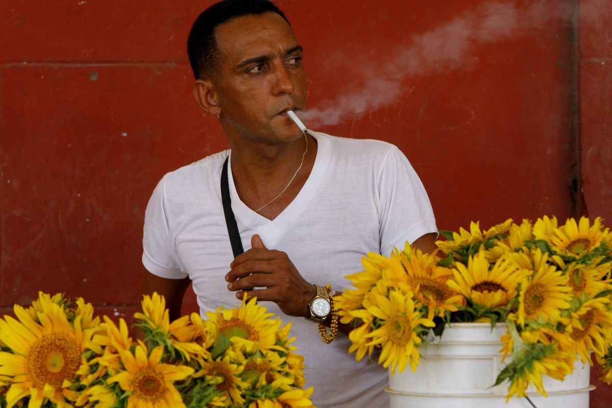 A flower vendor smokes a cigarette in Havana. The communist government announced Wednesday it is cutting cigarettes from ration books effective Sept. 1. (Associated Press)