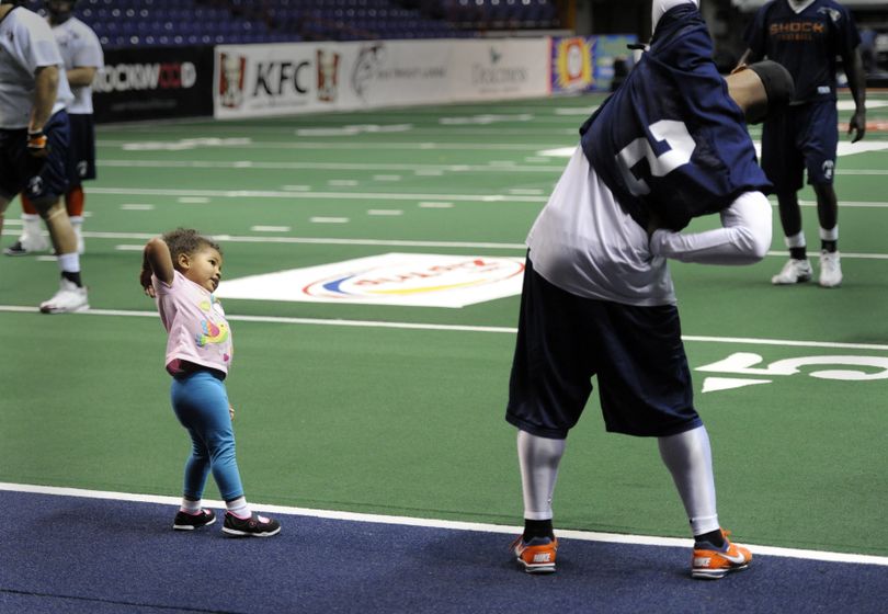 Tiana Sanders, 2-year-old daughter of the Spokane Shock's Terrance Sanders, stretches with defensive back Josh Ferguson. (Jesse Tinsley)