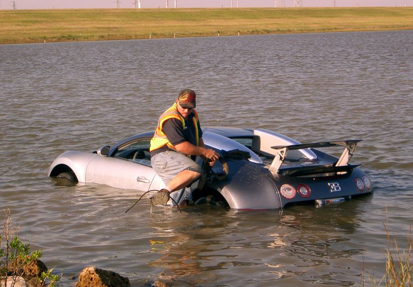 In this Wednesday, Nov. 11, 2009 photo, wrecker driver Gilbert Harrison, with MCH Towing, attaches a towing cable to a Bugatti Veyron that was driven into the water near Omega Bay in La Marque, Texas. A man blamed  a low-flying pelican and a dropped cell phone for his veering his million-dollar sports car off a road and into a salt marsh near Galveston. (Chris Paschenko / The Galveston County Daily News)