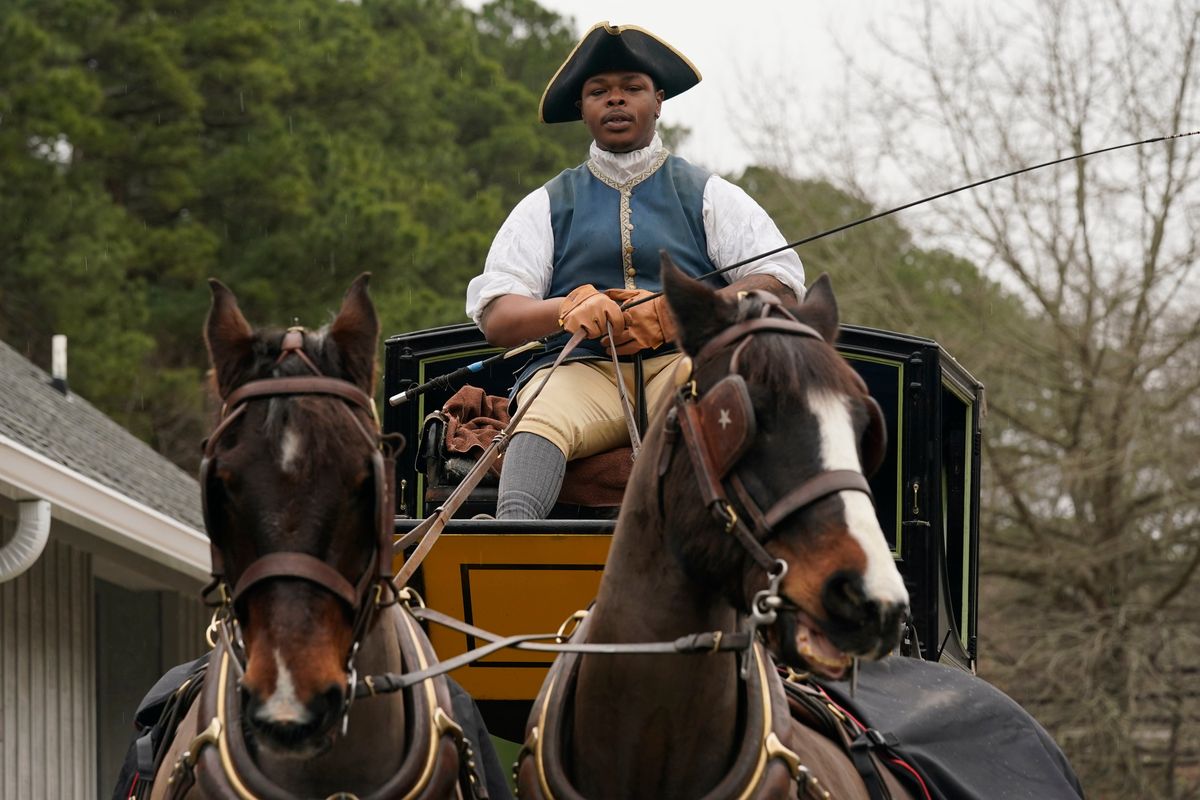 Colonial Williamsburg coachman Collin Ashe directs his horses as he drives his coach Thursday Feb. 24, 2022, in Williamsburg, Va. Colonial Williamsburg has begun to honor the coachmen by naming a new carriage after one of them.  (Steve Helber)