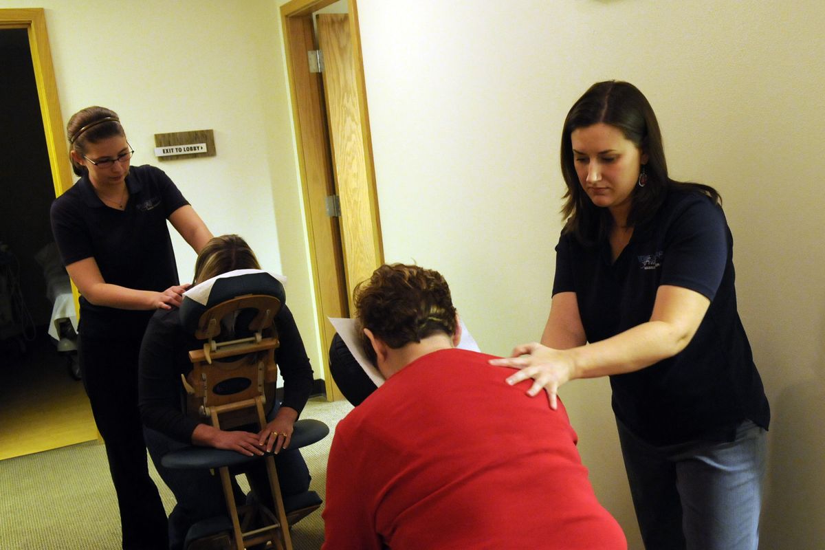 Samatha Pizzato, left, and Serena McMillan of Whispering Falls Professional Message provide massages during a mammogram party at the Inland Imaging screening center in Spokane Valley on Nov. 21. (J. Bart Rayniak)