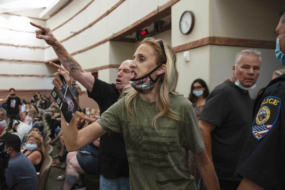  In this Aug. 12, 2021 photo, protesters against a COVID-19 mandate gesture as they are escorted out of the Clark County School Board meeting at the Clark County Government Center, in Las Vegas. A growing number of school board members across the U.S. are resigning or questioning their willingness to serve as meetings have devolved into shouting contests over contentious issues including masks in schools.  (Bizuayehu Tesfaye)