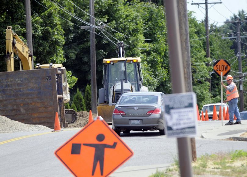 Flaggers direct traffic on Bowdish Road just south of Sprague, July 11,while utility work is completed in the area. There have been several cases so far this year where utility workers have severed natural gas lines in Spokane Valley in residential neighborhoods.  (J. Bart Rayniak)