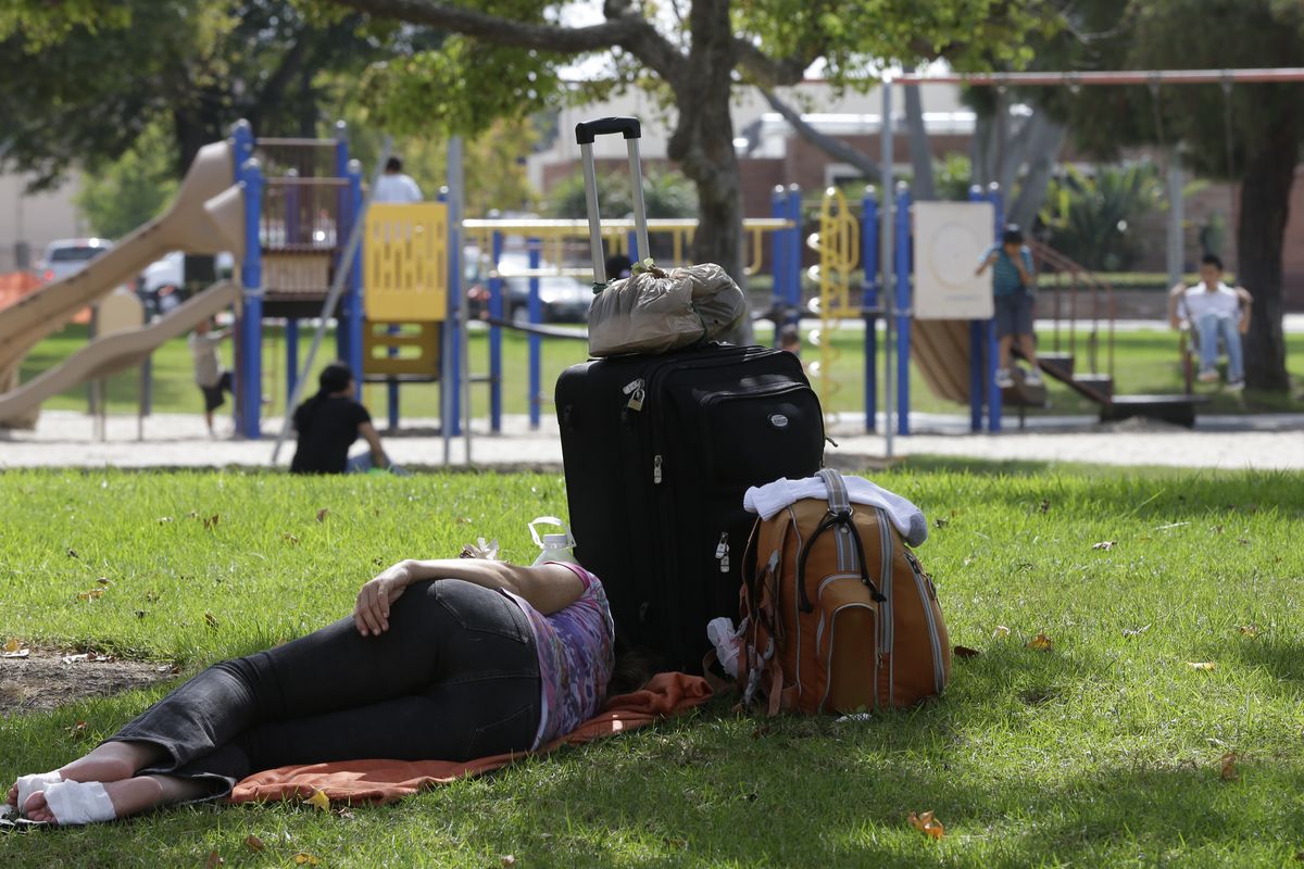In this photo taken Saturday, Oct. 6, 2012, a homeless woman rests under a shade tree as children play at Lions park in Costa Mesa, Calif. The posh California coastal town recently passed a law banning patrons from lounging on furniture in its public libraries, having poor personal hygiene or emitting an odor bothers others. The ordinances are the latest in a rash of law-making in Orange County cities that some see as thinly veiled attacks on the homeless. But lawmakers defend the policies as necessary to ensure safety, protect public property and guarantee access to communal spaces. (Chris Carlson / Associated Press)