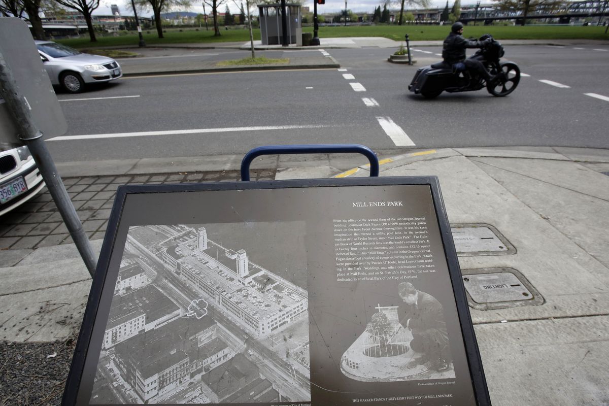 A plaque illustrates the history of Mill Ends Park, located just to the left of a passing motorcyclist, in Portland. Tiny battle lines are being drawn in a whimsical British-American dispute over which country has the world’s smallest park. (Associated Press)