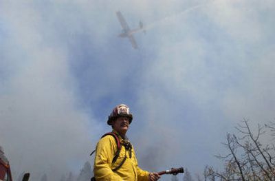 
Smoke fills the air as Spokane County Fire District 9 Capt. Dan Walsh works on the ground. A water tanker flies overhead and drops a load on a 10-acre fire at Market and Hawthorne on Thursday.
 (Dan Pelle / The Spokesman-Review)