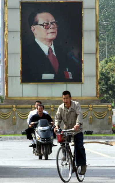 
A bicylclist and motorcyclist pass by a large portrait of former Chinese President Jiang Zemin in Beijing on Sunday. 
 (Associated Press / The Spokesman-Review)