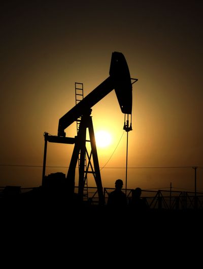 Oil workers are seen at an oil pump at sunset Wednesday in the desert oil fields of Sakhir, Bahrain. Regulators say excessive speculation is driving up the cost of oil and wheat. (Associated Press)