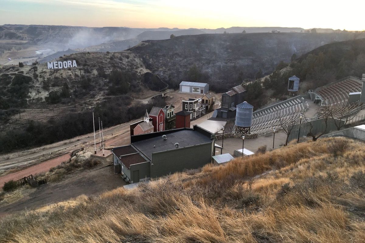 A wildfire smolders near the Burning Hills Amphitheatre Thursday, April 1, 2021 near Medora, N.D. Officials say firefighters have stopped a wildfire from spreading in the western North Dakota tourist town of Medora, where its 100 residents were forced to evacuate.  (Tom Stromme)