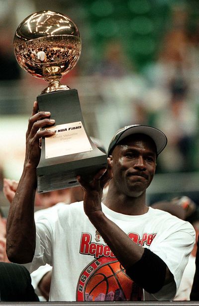 Michael Jordan holds aloft his MVP trophy after the Bulls won their 6th NBA championship — this one against the Utah Jazz on June 14, 1998.  (Tribune News Service)