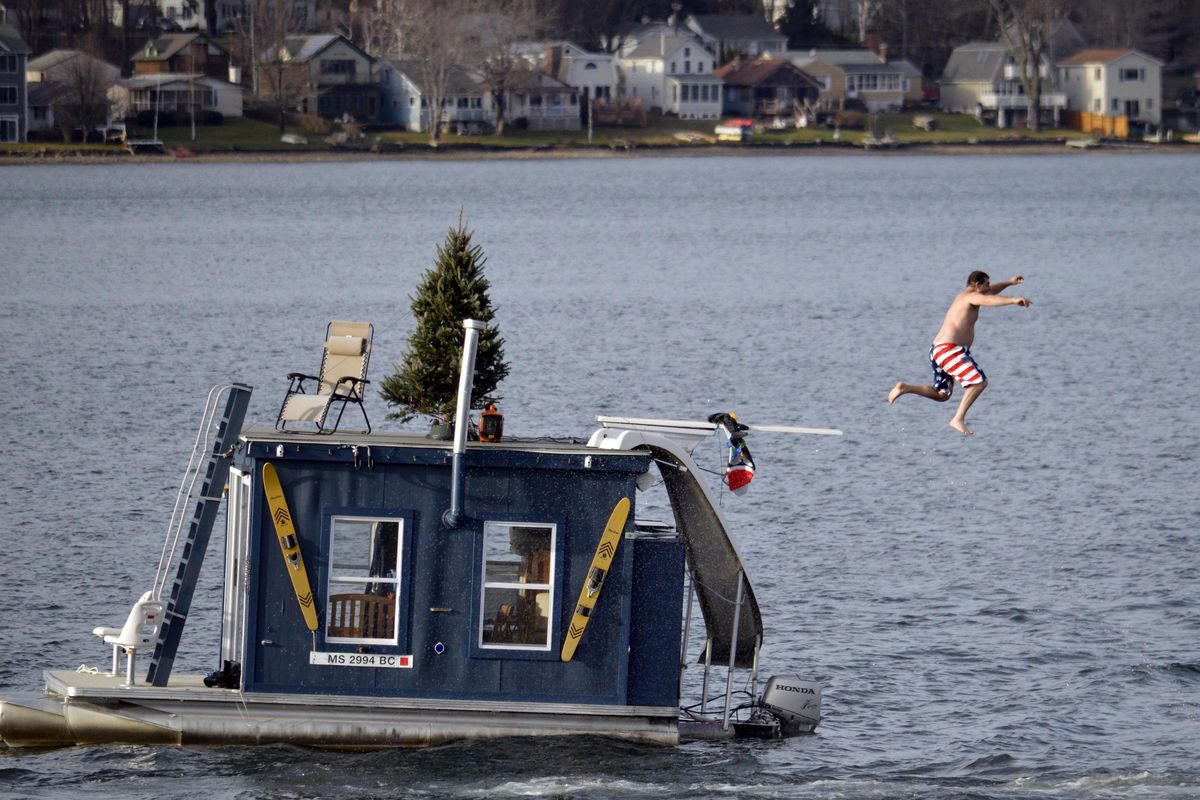 In this Dec. 24, 2015, file photo, a man jumps into Pontoosuc Lake in Pittsfield, Mass. The New England lake is typically frozen in December, but unusually warm temperatures have kept the water open. On Thursday, Oct. 18, 2018, the National Weather Service forecasted a warmer than normal 2018-2019 winter for the northern and western three-quarters of the U.S. (Ben Garver / Associated Press)