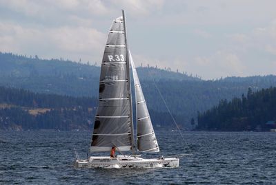 Miles Moore places a daggerboard in its place on his R33 catamaran, which he uses for sailing lessons and cruises, while cruising across Lake Coeur d’Alene Tuesday afternoon. The weather turned from miserably hot Monday to cool and breezy Tuesday, chasing many away from the lake.  (Jesse Tinsley / The Spokesman-Review)
