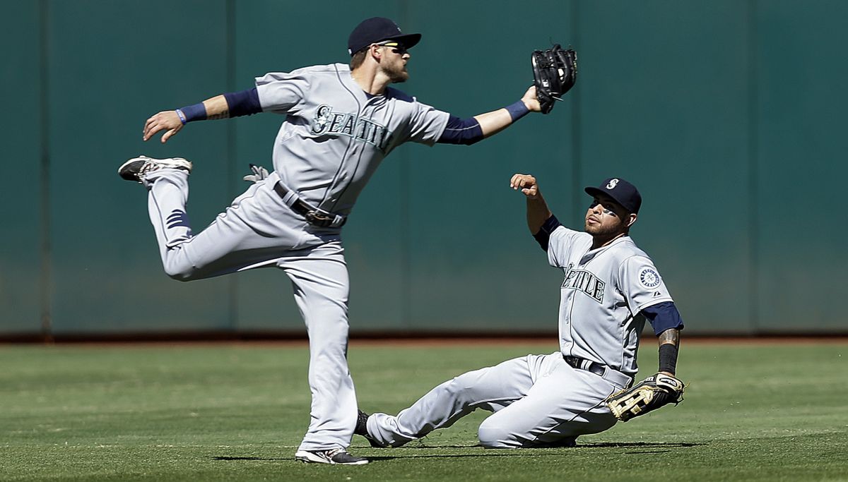 Mariners’ Shawn O’Malley, left, catches a ball in front of Stefen Romero, ending an Oakland threat in the seventh. (Associated Press)