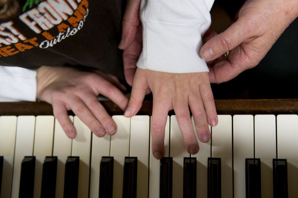Board certified music therapist Carla Carnegie helps client Alex Owens, 8, who is blind, play a simple song on the piano. Carnegie, owner of Willow Song Music Therapy Center in Otis Orchards, has been working for four years in private practice serving individuals and groups living with wide variety of neurological issues like Alzheimer