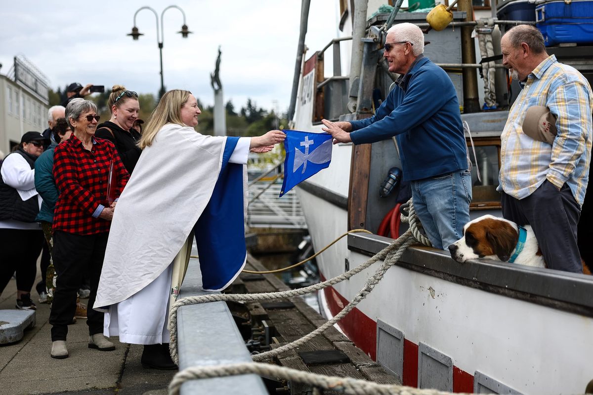 Pastor Mary Elise Scott hands a pennant to David Christensen, owner of the fishing vessel Gjøa, Sunday during the 98th annual Blessing of the Fleet ceremony at Fishermen’s Terminal in Seattle. (Nick Wagner/The Seattle Times/TNS)