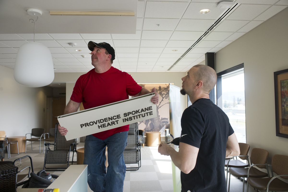 Todd Kroll, left, and Nate Matthews hang signs in a clinic waiting room at the new Providence Medical Park Spokane Valley on Wednesday. The center is scheduled to open for business April 28. (Jesse Tinsley)