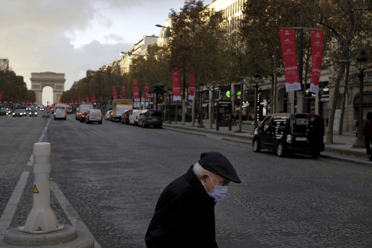 An elderly man wears a face mask as he walks on the Champs Elysee avenue, in Paris, Thursday, Nov. 19, 2020. France has surpassed 2 million confirmed cases of coronavirus, the fourth-highest total in the world.  (Thibault Camus)