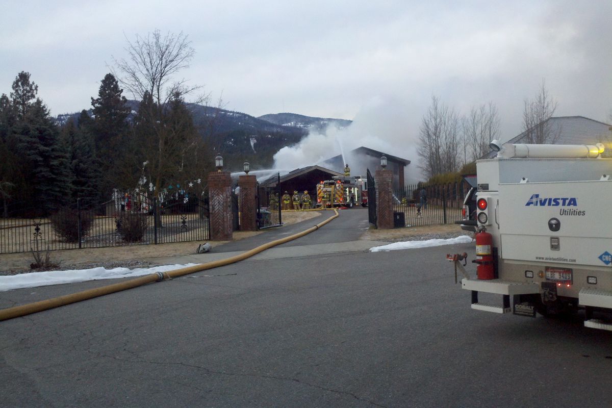 Firefighters this morning at the scene of a mansion fire along the Spokane River in Post Falls. (Jesse Tinsley)