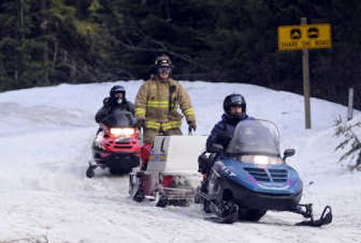 
Kootenai County sheriff's deputies and a firefighter return to the parking area at Fourth of July pass after recovering the body of a snowmobiler  Wednesday. 
 (Jesse Tinsley / The Spokesman-Review)