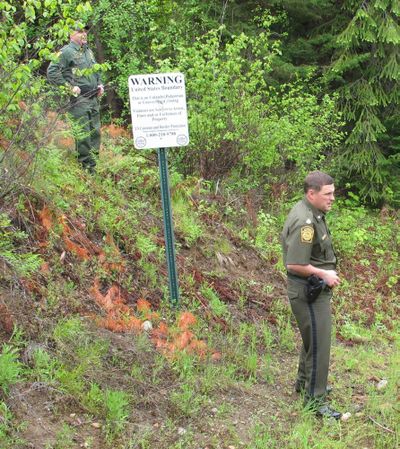 In this June 4, 2010 photo, U.S. Border Patrol agents Shannon Clift, left, and Lonnie Moore, right,  stand on the U.S.-Canadian border in thick forest near Metaline Falls, Wash.  The agents often use horses to look for smugglers in the forested mountains along the Canadian border, but now will be adding a more modern tool to help them keep watch, text messaging. The agency on Tuesday began asking residents, campers, hunters and other outdoor enthusiasts to send anonymous text messages to report suspicious people they come across in the lightly populated area from Washington to Montana. (Nicholas Geranios / Associated Press)