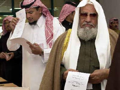 
Abdel Aziz al-Juhani, 70, right, and other Saudi men check their voter registration cards as they line up to cast their ballots on Thursday in Riyadh. 
 (Associated Press / The Spokesman-Review)