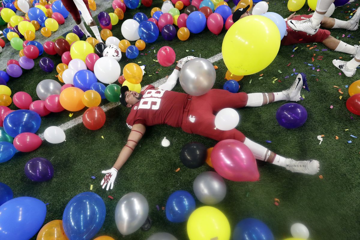 Washington State defensive lineman Dallas Hobbs rolls between balloons as he celebrates the Cougars’ 28-26 win over Iowa State in the Alamo Bowl on Dec. 28, 2018, in San Antonio. Hobbs, a redshirt senior, majored in digital technology and culture.  (Associated Press)