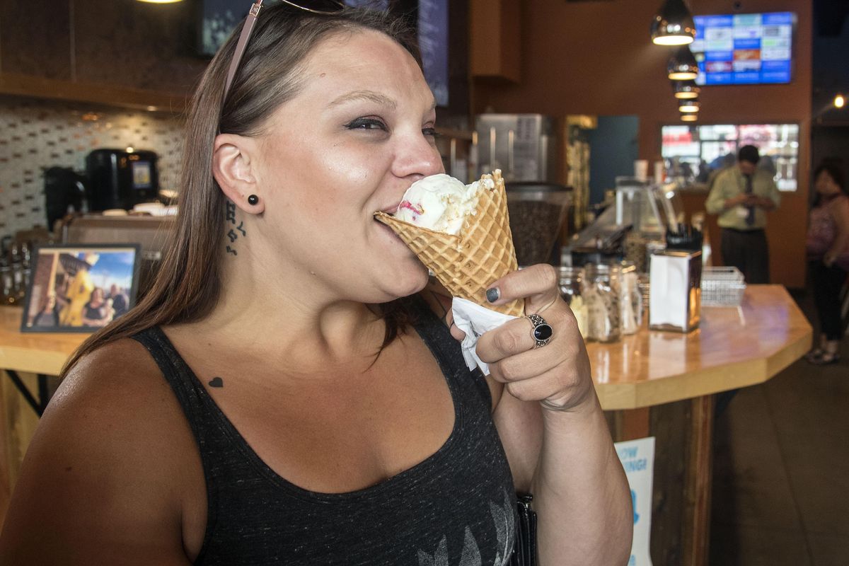 Angie Koep, of Spokane Valley, Wash., bites into cake ice cream with animal cookies from Brain Freeze Creamery, July 7, 2017. (Dan Pelle / The Spokesman-Review)