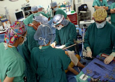 Dr. Rebecka Meyers, center with headlamp, works with other hospital staff to separate conjoined twins Kendra and Maliyah Herrin at Primary Children's Medical Center on Monday in Salt Lake City.
(Associated Press photos / The Spokesman-Review)