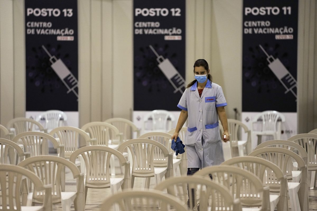 FILE - A worker disinfects chairs at a new vaccination center in Lisbon, Tuesday, Nov. 30, 2021. A pandemic-weary world faces weeks of confusing uncertainty as countries restrict travel and take other steps to halt the newest potentially risky coronavirus mutant before anyone knows just how dangerous omicron really is.  (Armando Franca)