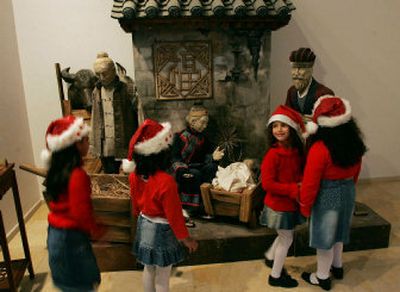 
Palestinian girls wearing Santa Claus hats look at a display at an exhibition of Nativity sets at the Peace Center in Bethlehem's Manger Square.
 (Associated Press photos / The Spokesman-Review)