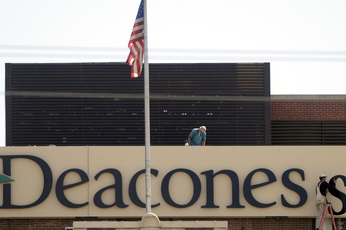 Workers hang letters for a new sign at Deaconess Medical Center on Aug. 25, 2009, shortly after the hospital was purchased by Tennessee-based Community Health Systems. As part of a settlement with the Empire Health Foundation, CHS has agreed to forgive up to $50 million in medical debt for people who received treatment at Deaconess and Valley hospitals between 2008 and 2017. (Jesse Tinsley / The Spokesman-Review)