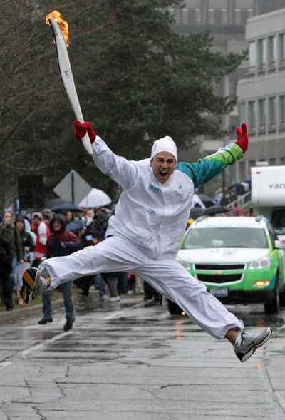 Torchbearer Michael Tchao jumps as he carries the Olympic flame during the Olympic torch relay at Simon Fraser University in Burnaby, B.C., on Thursday.  (Associated Press)