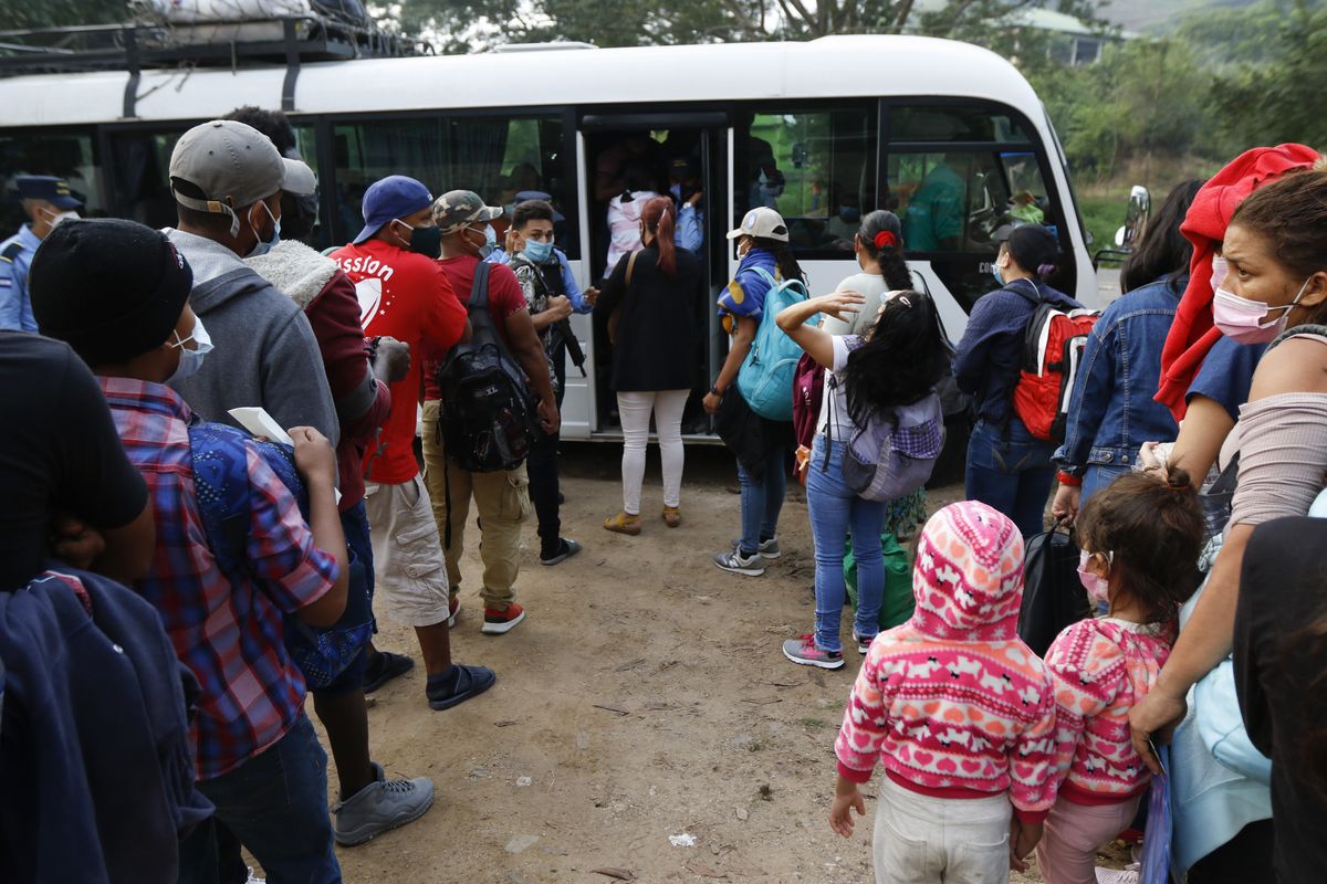 Honduran migrants trying to reach the U.S. border as a group board a public bus on the highway to Santa Barbara, early Friday, Jan. 15, 2021. The migrants left with little certainty about how far they will make it as regional governments appeared more united than ever in stopping their progress.  (Delmer Martinez/Associated Press)