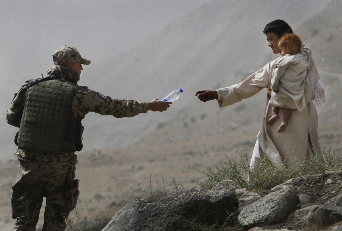 An ISAF soldier with the German Federal Armed Forces offers water to an Afghan man and his child during a patrol in the mountains above Feyzabad, northern Afghanistan, on Wednesday. Associated Press photos (Associated Press photos / The Spokesman-Review)
