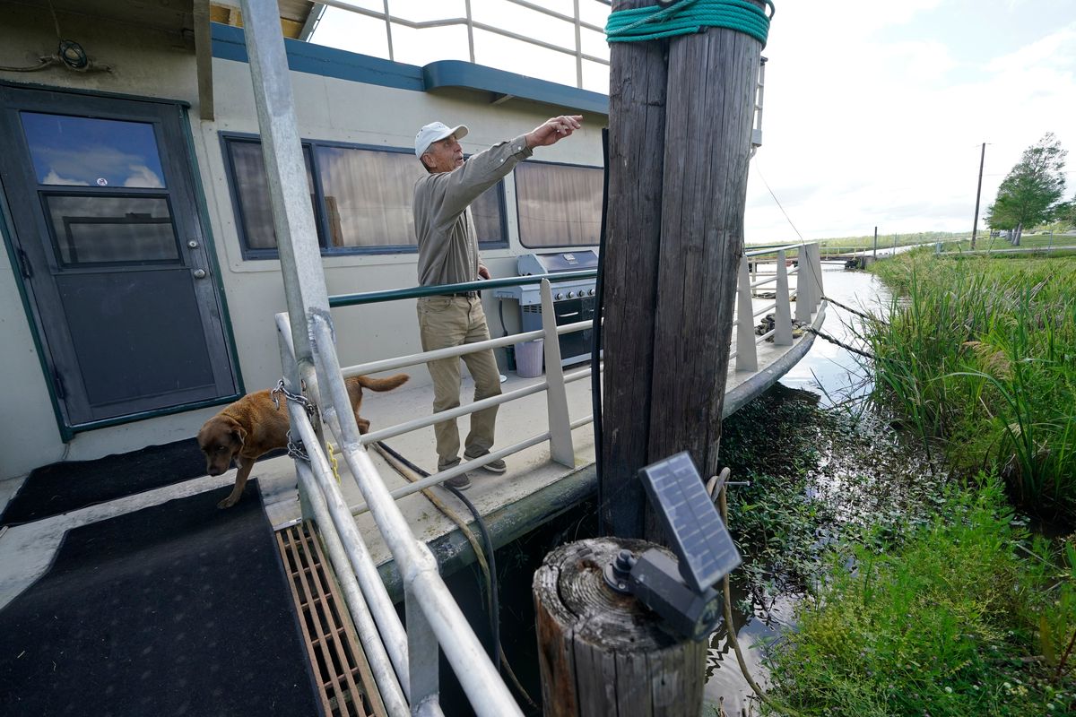 Ted Falgout points out the storm’s waterline standing on the houseboat on his property that he rode out Hurricane Ida and has been living in while his home undergoes extensive repairs, in Larose, La., Thursday, April 14, 2022. As climate change increases the threat of hurricanes, cities on the Louisiana coast and Mississippi River are hoping President Biden’s $1.2 trillion infrastructure package will provide badly needed funding to fortify locks, levees and other flood protections.  (Gerald Herbert)