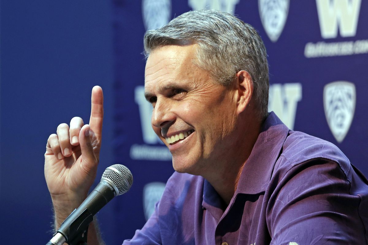 Washington NCAA college head football coach Chris Petersen points skyward in response to hearing Blue Angels jets soar nearby as he speaks at a news conference Thursday, Aug. 2, 2018, in Seattle. (Elaine Thompson / Associated Press)