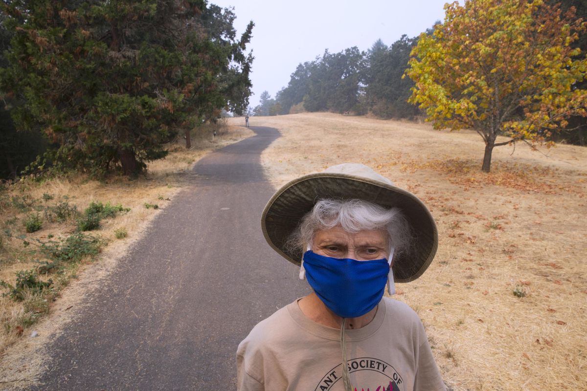 With a precautionary face mask protecting her from the smoky air, Kathleen Soza pays a visit to Skinner Butte Park in Eugene, Ore. with family and friends Monday Sept. 4, 2017, as smoke from nearby wildfires cause health concerns for area residents. (Chris Pietsch / Associated Press)