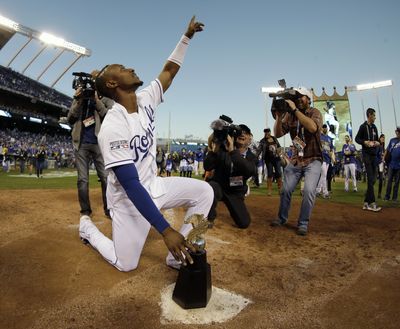 Kansas City Royals' Jarrod Dyson puts the championship trophy on home plate after the Royals defeated the Baltimore Orioles to win the American League baseball championship series Wednesday in Kansas City, Mo. (Associated Press)