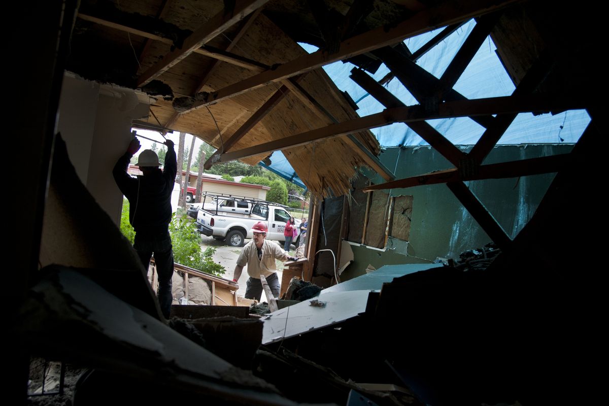 Stacy Vanderberg, left, and Shaun Krantz, of Belfor Property Restoration, shore up a home that was damaged by a falling tree during Wednesday’s thunderstorm near the corner of Alameda Boulevard and Crown Avenue in north Spokane. (Dan Pelle)
