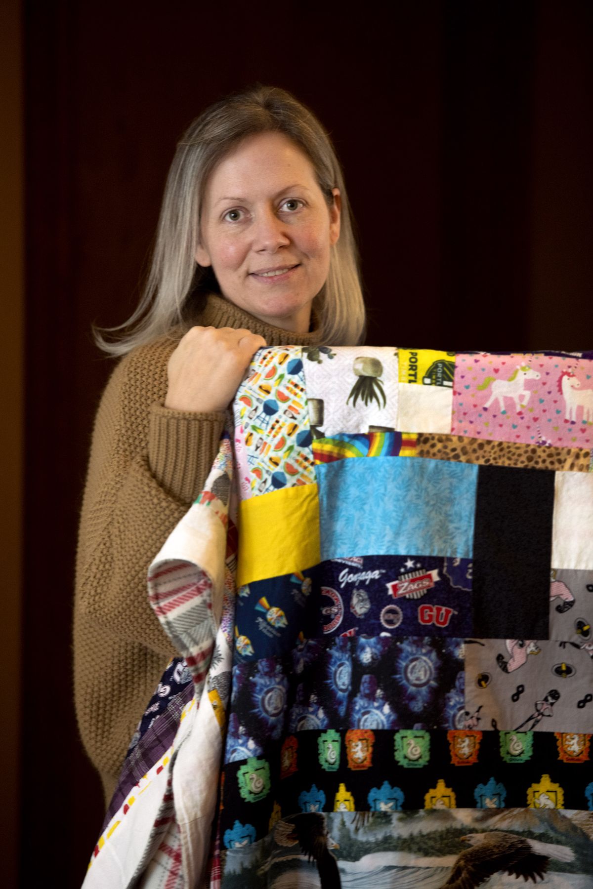 Holly Jones is photographed at her home in Spokane Valley on Feb. 2, 2021, with the quilt made out of scraps from masks she sewed during the pandemic.  (Kathy Plonka/The Spokesman-Review)