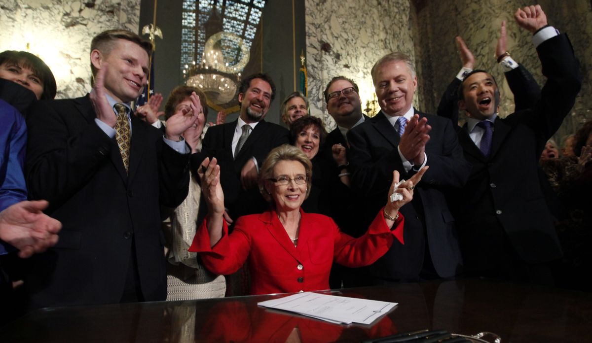 Washington Gov. Chris Gregoire, seated, raises her arms as legislators and supporters cheer behind her after she signed into law a measure that legalizes same-sex marriage Monday in Olympia. (Associated Press)