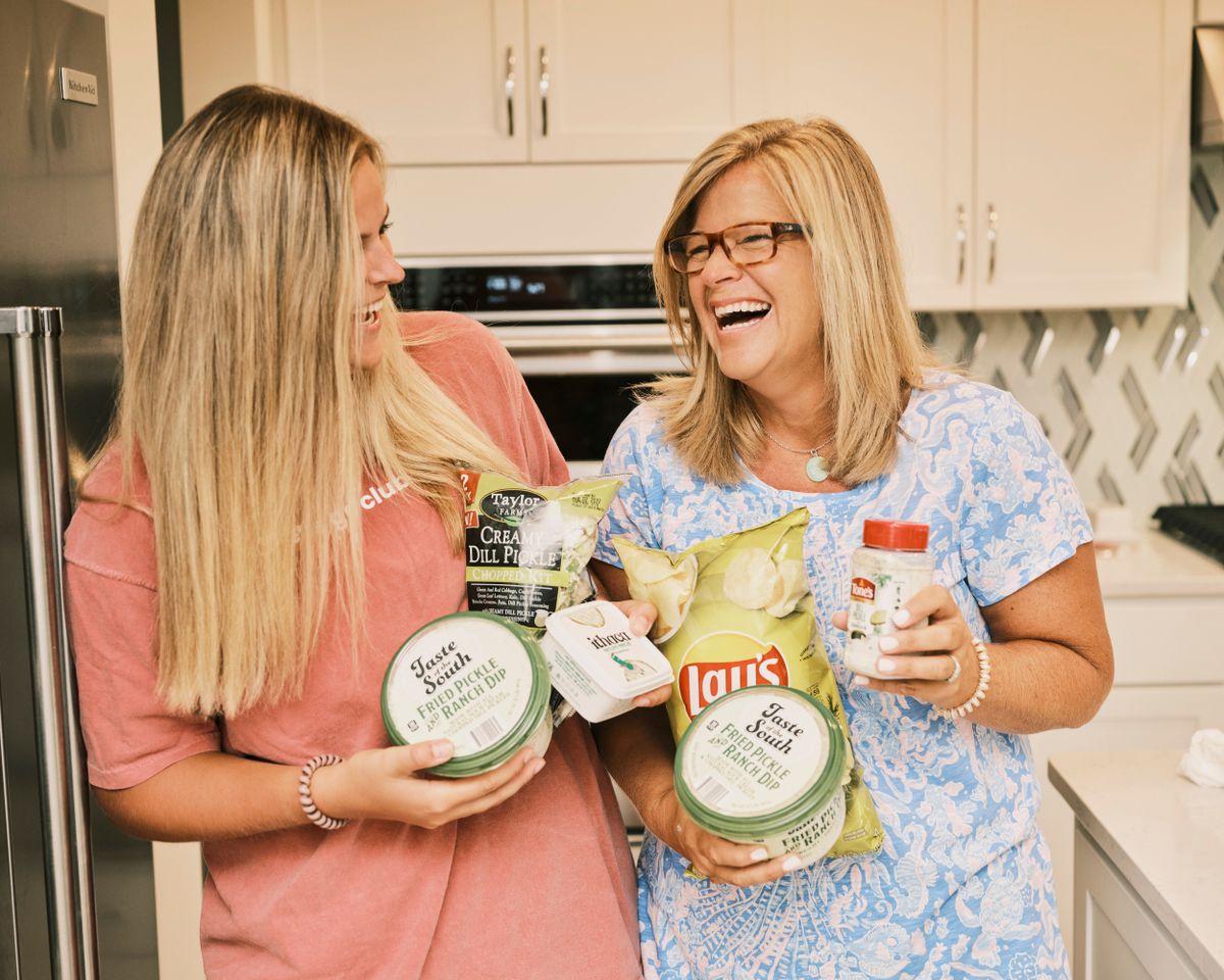 Maddie, left, and Meg Antonelli hold assorted pickle-flavored foods at home in Bradenton, Fla., on July 30. The mother-daughter duo review foods from warehouse stores on TikTok, but they’ve also made a name tasting pickle-flavored products.  (Zack Wittman/The New York Times)
