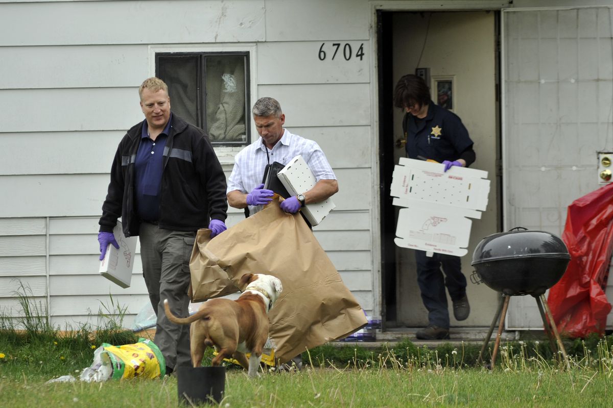 Detective Michael Drapeau, front, and investigators with the Spokane County Sheriff’s Office remove evidence from a house at 6704 E. Third Ave., where Shane Smith, 38, was arrested Tuesday afternoon in connection with the homicide of Warren Flinn. (Colin Mulvany)