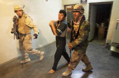 
A U.S. Marine, left, and an Iraqi soldier lead a man through his house during a raid Wednesday in Saadah, Iraq, near the Syrian border. 
 (Associated Press / The Spokesman-Review)