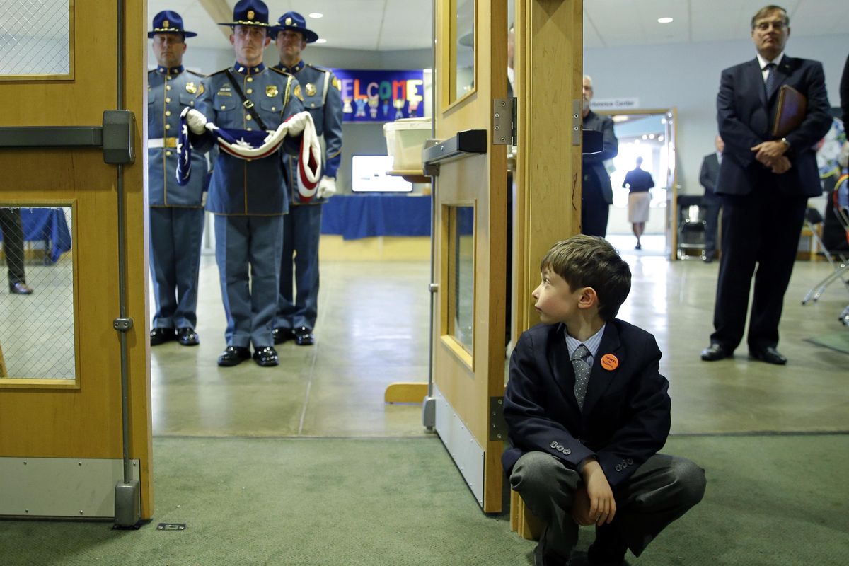 Lucas Oakes, 6, a grandson of former Washington Gov. Mike Lowry, watches as a Washington State Patrol honor guard holds a U.S. flag outside a memorial service for Lowry, Tuesday, May 30, 2017, in Renton, Wash. (Ted S. Warren / Associated Press)